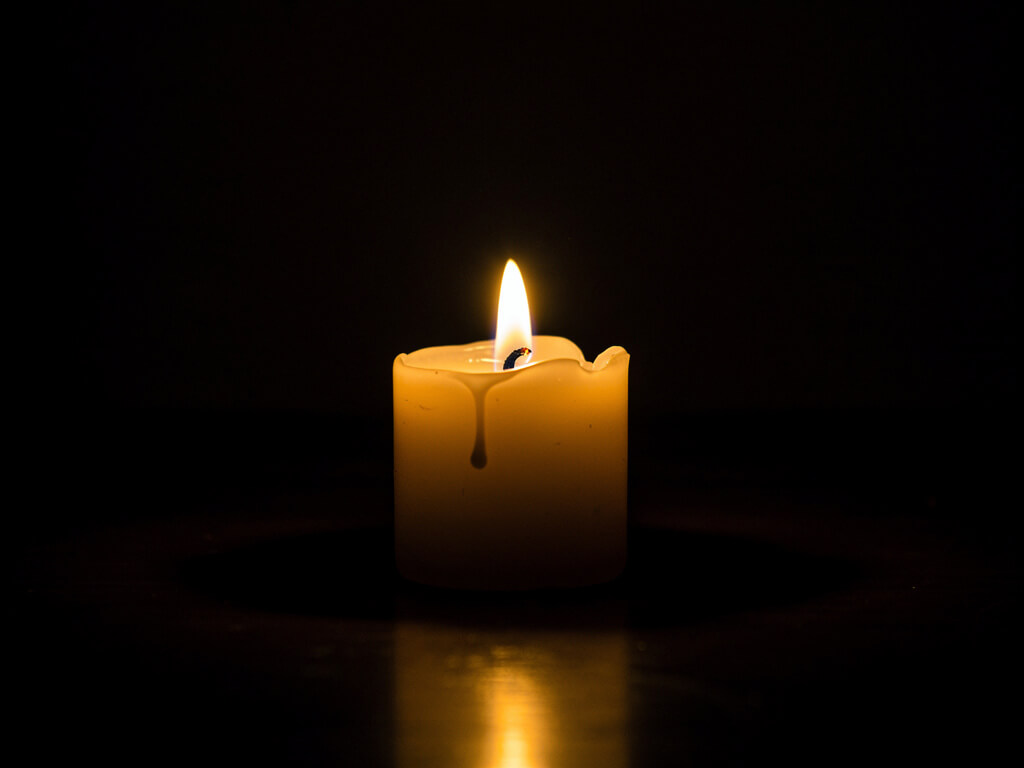 Bright steady candle flame burning cleanly in a dark room, warm stable glow, calm and sustainable, centered composition, dark background, studio lighting